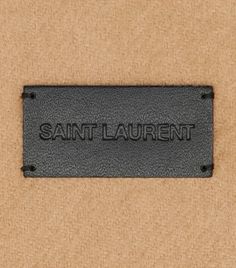 the name saint laurent is engraved in black on a tan background with dark metal fittings