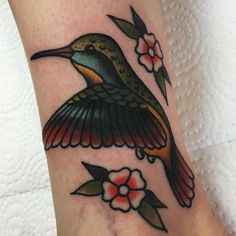 a hummingbird tattoo on the ankle with flowers