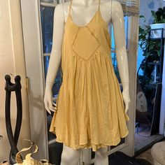 a mannequin wearing a yellow dress in front of a window