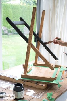 a woman is working on an easel made out of wood and plywood planks