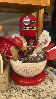 a red and white mixer sitting on top of a counter next to other kitchen items