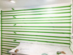 the wall is painted green and white with strips of paint on it, along with tape