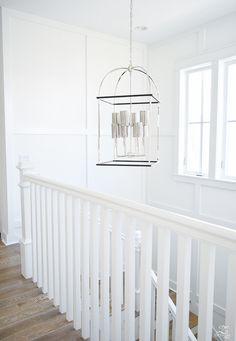 a chandelier hanging from the side of a white staircase