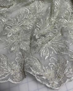 the fabric is white and has silver flowers on it's side, with an intricate design