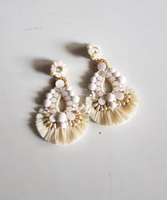 "Bohemian Ivory raffia statement wedding earring. This intricate handcrafted gold accent statement earring is just perfect for your D day.Made of elements like frosted glass beads, faux pearl, seed beads, mop, shell, golden thread, sequin and added with raffia fringes. A complete head Turner. The Earrings measure about approx. 3.60\" long and 2.60\" wide. PS: Carnation jewelry is handmade & handcrafted in India hence there is a possibility of a slight or small imperfection due to the fact th Carnation Jewelry, Summer Wedding Jewelry, Statement Wedding Earrings, Statement Earrings Wedding, Bridal Earring, Wedding Earring, Golden Thread, Ivory Earrings, Ivory Bridal