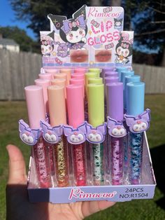 a person holding up a display of hello kitty lip glosses