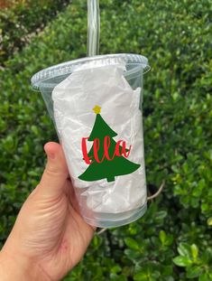 someone holding up a plastic cup with a christmas tree on it