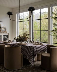 a dining room table is set with place settings and chairs, while the windows are open