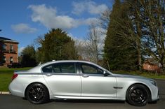 a silver car parked on the side of a road next to a lush green field