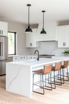 a kitchen with white cabinets and marble counter tops, four bar stools in front of the island