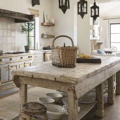 a large wooden table in a kitchen with lots of pots and pans on it