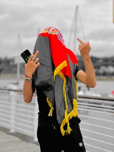 a woman wearing a red and grey scarf is holding her cell phone up in the air