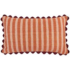 an orange and white striped pillow with pom poms on the bottom, in front of a white background