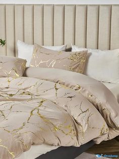 the comforter is made up and has gold leaf designs on it, along with two pillows