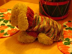 a teddy bear sitting on top of a wooden table next to a potted plant