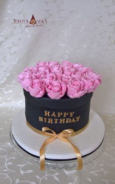 a birthday cake with pink roses in a black and gold hat on top of it