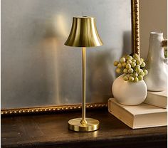 a table lamp sitting on top of a wooden table next to a vase with grapes