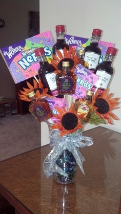 a vase filled with liquor bottles and sunflowers on top of a wooden table