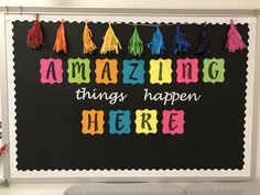 a blackboard with the words amazing things happen here written in multicolored letters