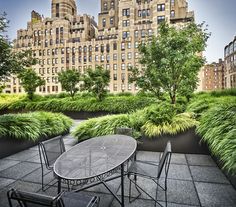 an outdoor table and chairs on a patio in front of a large building with lots of windows