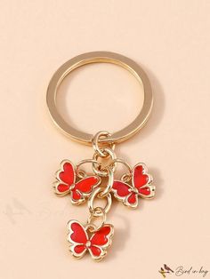 a red and gold keychain with three butterflies on it's back end