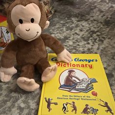 a stuffed monkey sitting next to a book