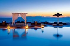 an outdoor swimming pool with candles lit up at night near the water's edge