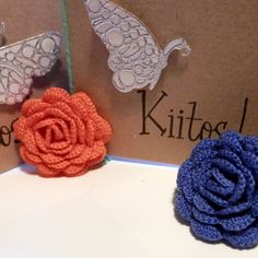 three crocheted flower brooch pins sitting on top of a card with the words hello kitty