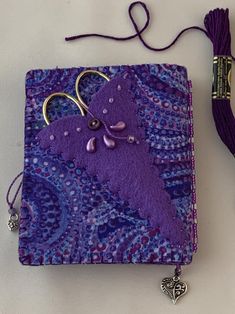 a purple and blue bag with some beads on it next to a tassell