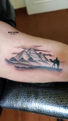 a man's arm with a mountain and horse tattoo on the left side of his arm