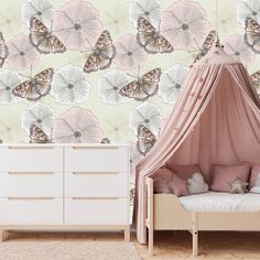 a child's room with pink and white flowers on the wall, a canopy bed and dresser