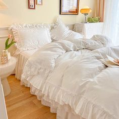 a bed with white ruffled bedspread and pillows