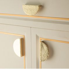 a close up of two knobs on a white cabinet with wood trim and gold accents