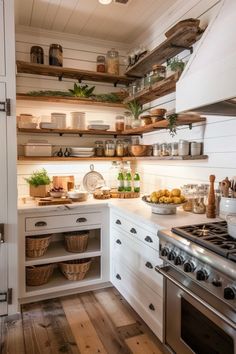 a kitchen with white cabinets and open shelvings on the wall above the stove