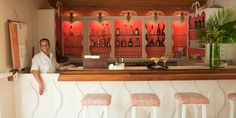 a man standing behind a bar with three stools