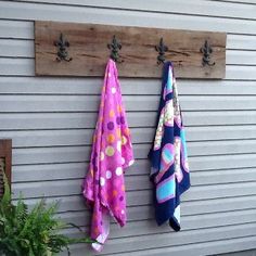 three towels hanging from hooks on the side of a house