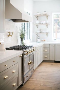 a kitchen with white cabinets and gold knobs on the stove top, along with wooden flooring