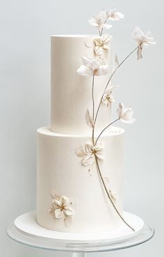 a three tiered cake with white flowers on it's side and frosting