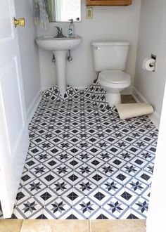 a white toilet sitting next to a sink in a bathroom under a mirror on top of a tiled floor