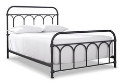 an iron bed frame with white sheets and pillows on the headboard, against a white background