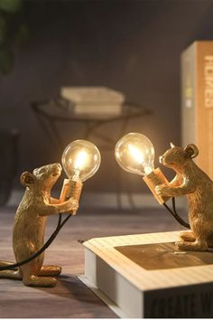 two light up mouse figurines sitting on top of a table next to books