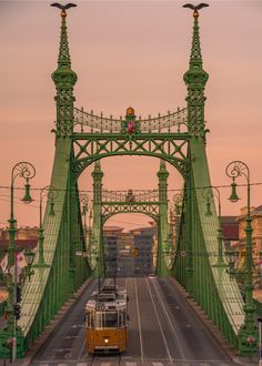 a train is going over a bridge in the evening time with traffic lights on it