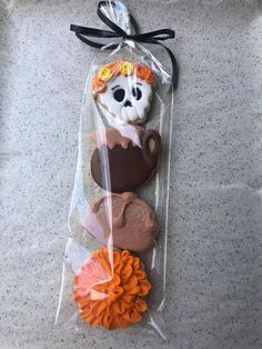 some cookies are in a plastic bag on the table and one is decorated like a skeleton