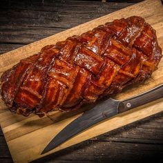 a large piece of meat sitting on top of a cutting board next to a knife