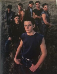 a group of young men standing next to each other in front of a grassy field