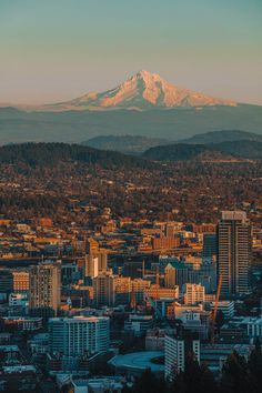 the city is surrounded by tall buildings and snow capped mountains in the distance, as seen from above