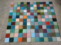 multicolored tiles are laid out on the ground to be used as wall art