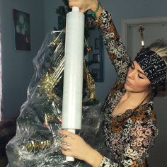 a woman is holding up a large white candle in front of a christmas tree with decorations on it