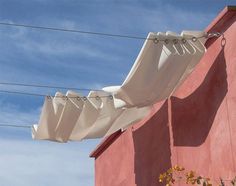 an umbrella is hanging on the side of a pink building with power lines in the background