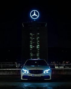 a mercedes car parked in front of a building with a neon sign on it's side